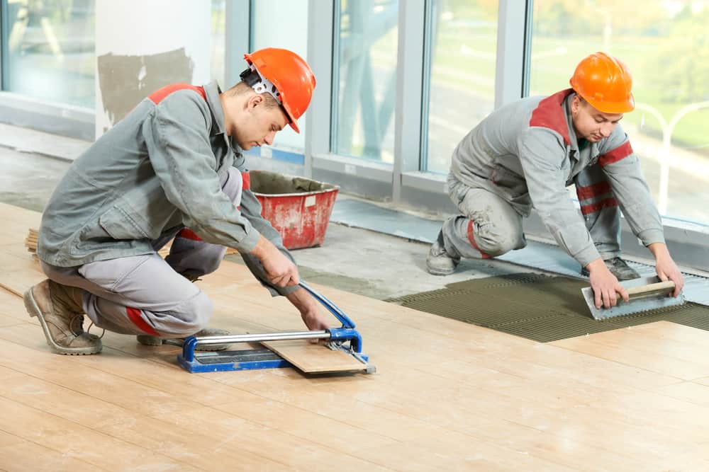 Two Industrial Tiler Builder Worker Installing Floor Tile At Repair