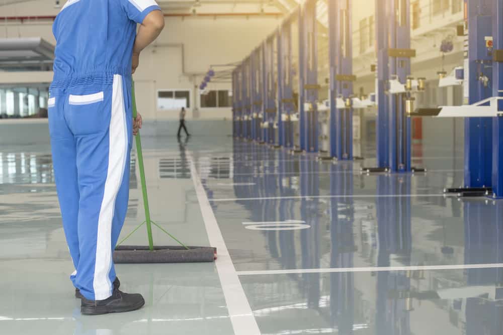 Worker In Blue Protective Uniform Cleaning New Epoxy Floor